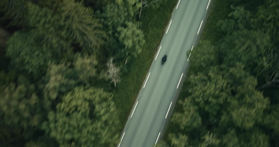 Motorcyclist travels through the forest during a road trip