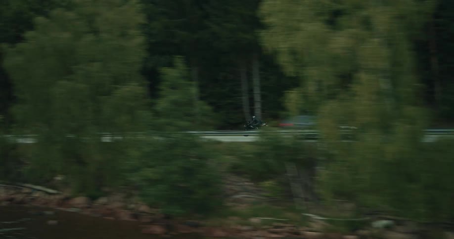 A person rides their motorcycle past the hills