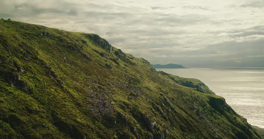 Aerial view of a green mountain by the sea