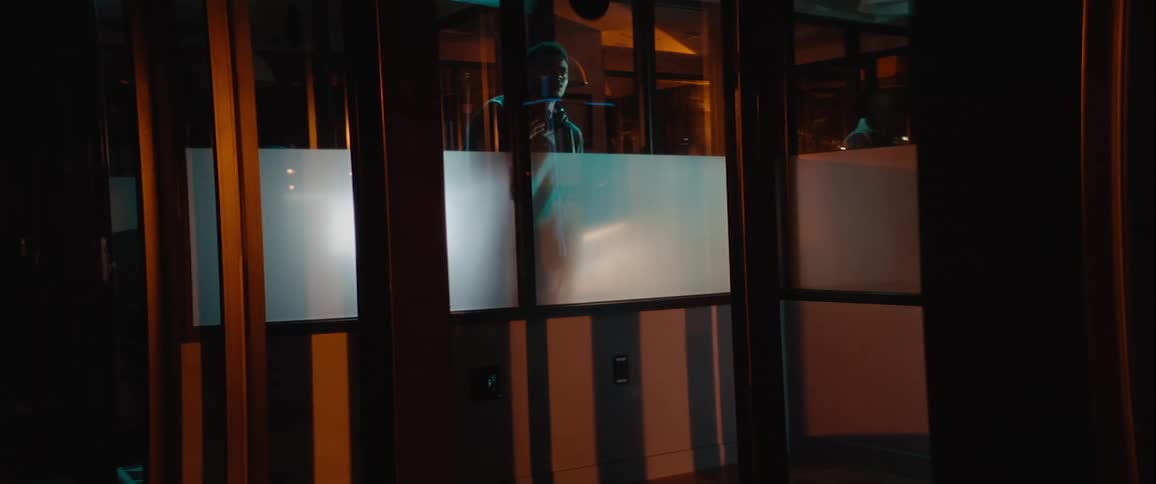 A man is peeking from outside through the windows of a house at night