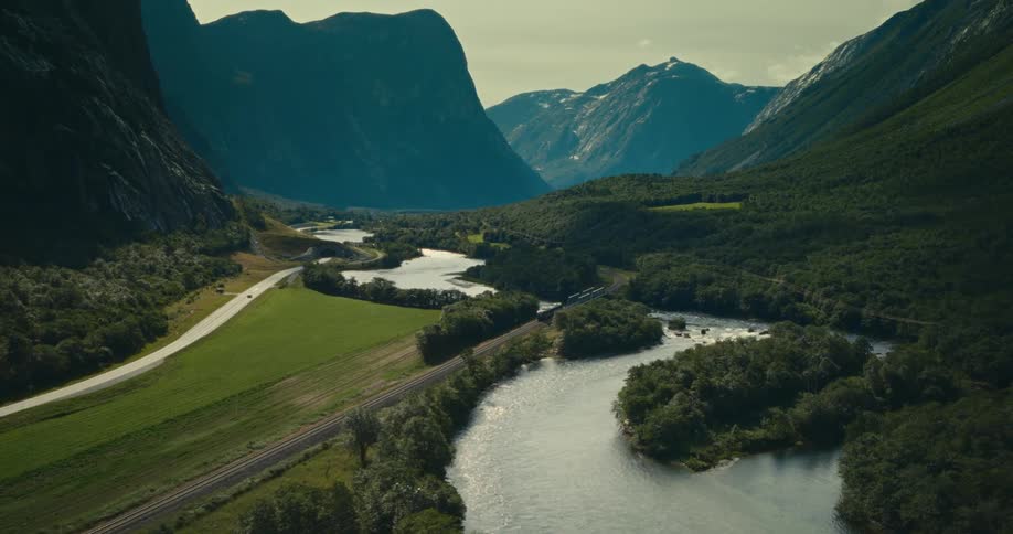 Train traveling through an area surrounded by lakes and a greenish mountain valley