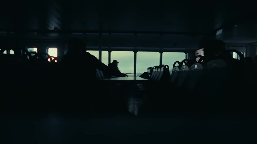 Silhouette of some people sitting on chairs on a moving boat in the ocean