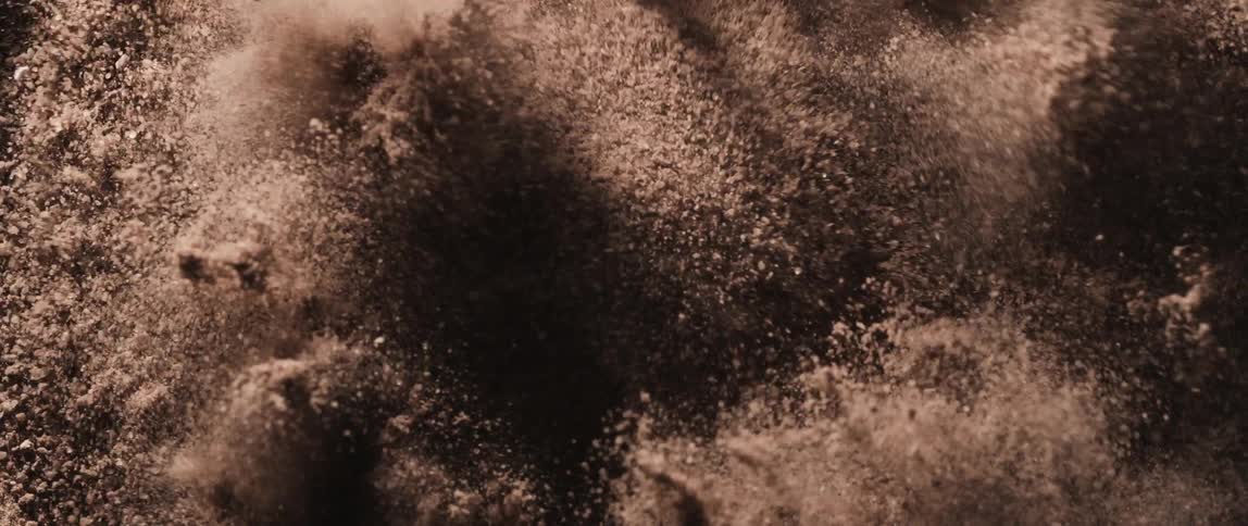 Close up of brown colored powder particles in abstract motion