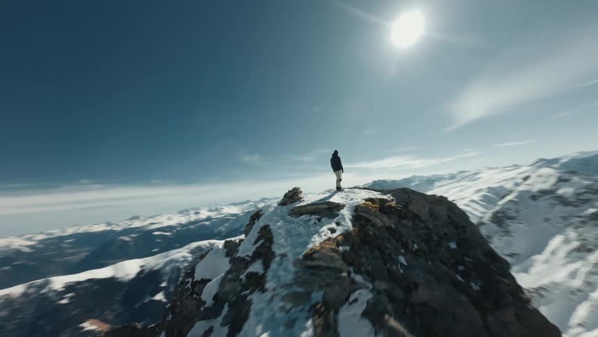 Man on top of a snow covered mountain cliff during daytime