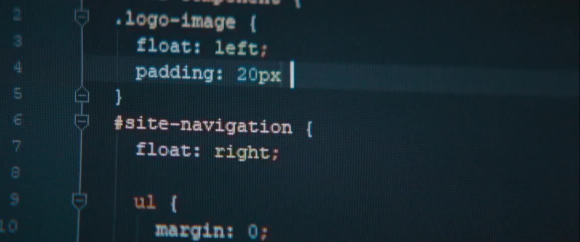 A closeup of a dark screen displays lines of computer code being written in realtime