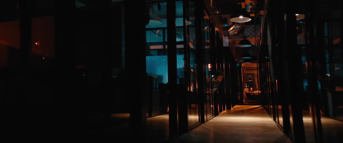 Man working alone after hours in a dim office leans into the hall to look around