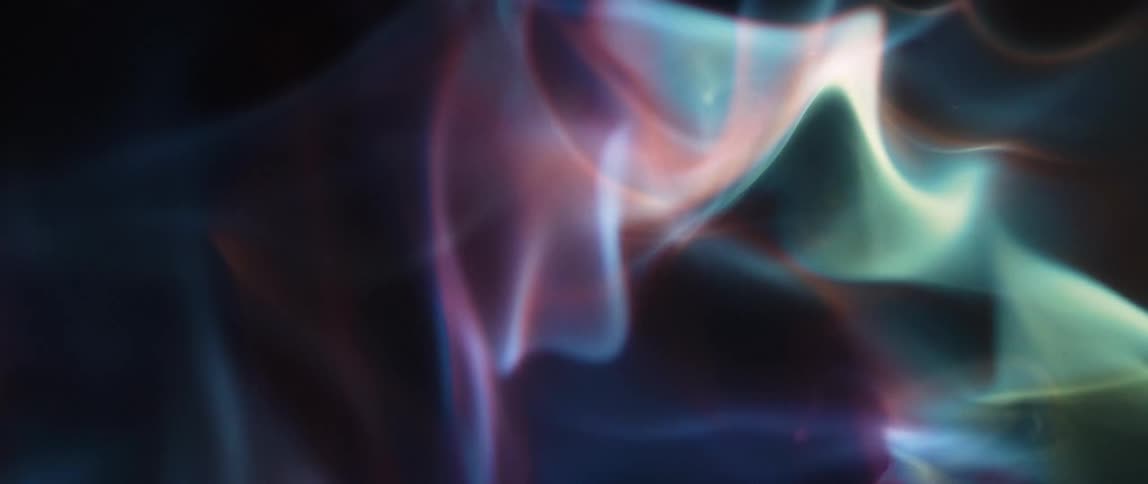 Swirling out of focus light patterns in shades of blue teal pink and white against a dark background