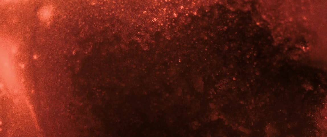 Extreme close up on a glowing reddish liquid in abstract motion