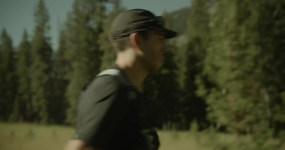 Man in cap running along a trail surrounded by trees