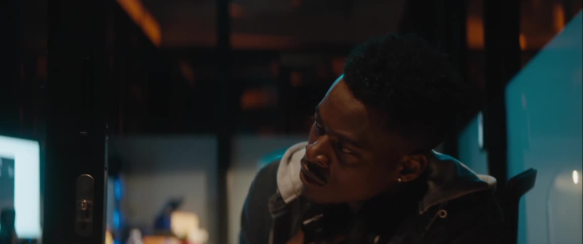 A black man looks back and forth while working in an office environment