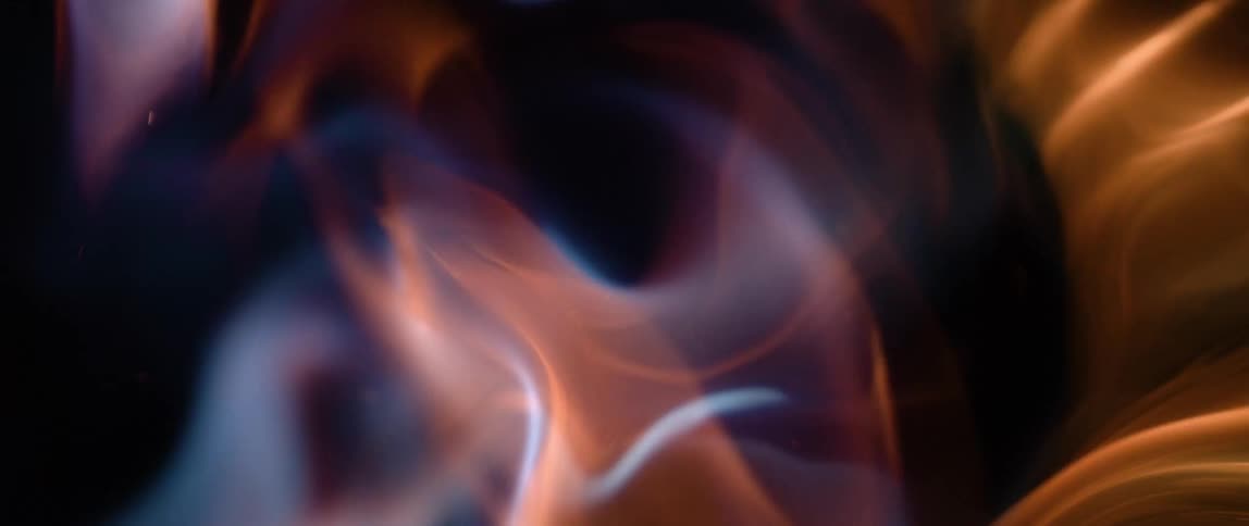 An abstract closeup shot captures vibrant flames intensely swirling and dynamically transitioning in hue from cool blue to warm orange showcasing the mesmerizing and unpredictable nature of fire
