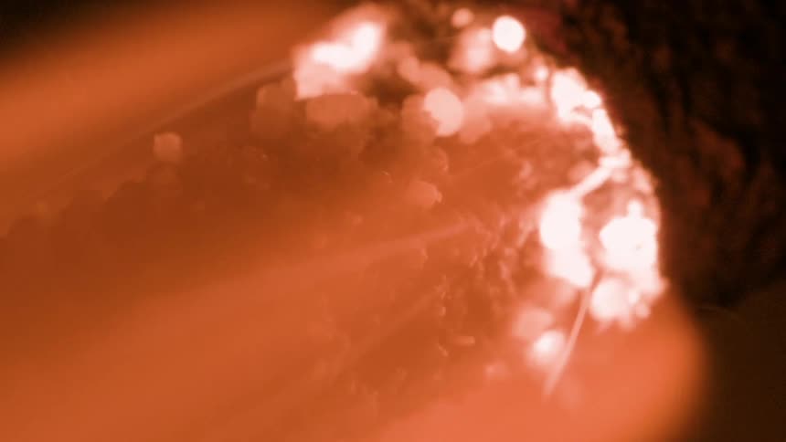 A burning object glows intensely covered in molten and ashy textures