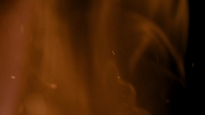 A flame glowing with warm golden hues against a dark background