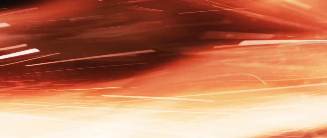 An abstract fiery background with rapidly moving streaks of orange yellow and white light resembling flames or sparks