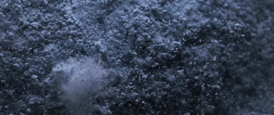 A closeup of fine powdery dust particles blasting up over a vibrating surface