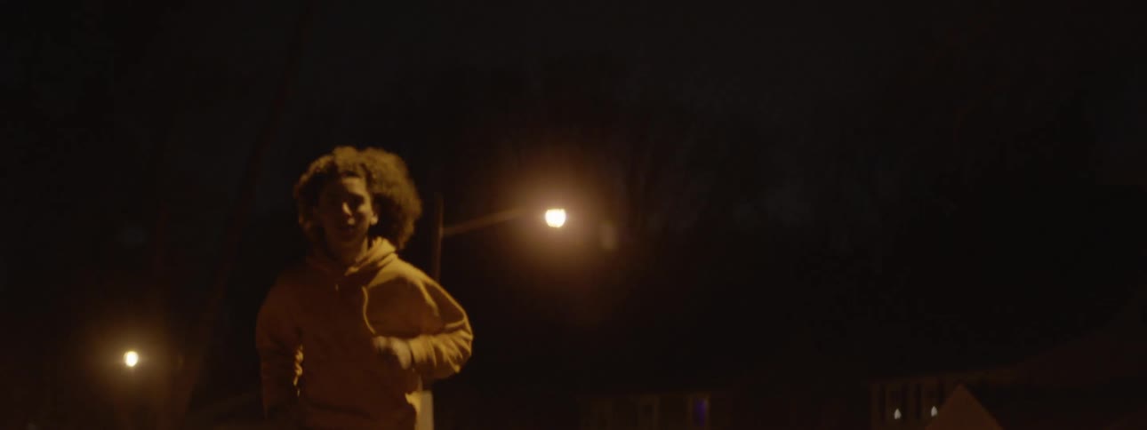 Curly haired person running alone on the street at night