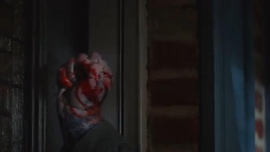 Persons hand with blood knocking on the door of a house