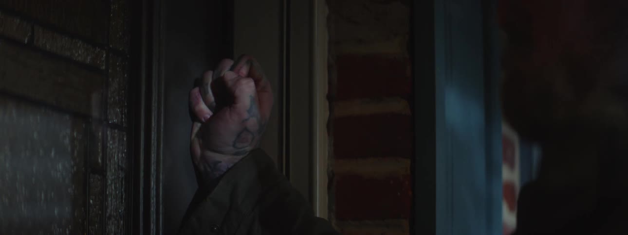Hand of an injured person knocking on a door of a house