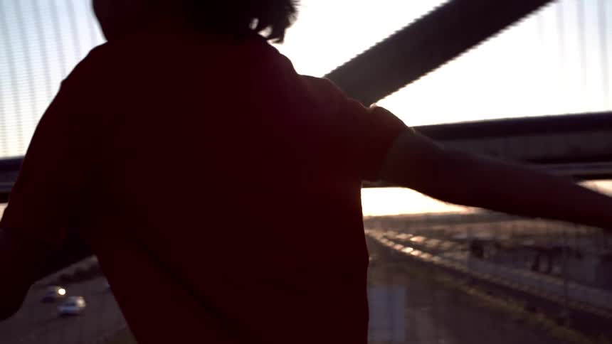 A boy runs across a city bridge