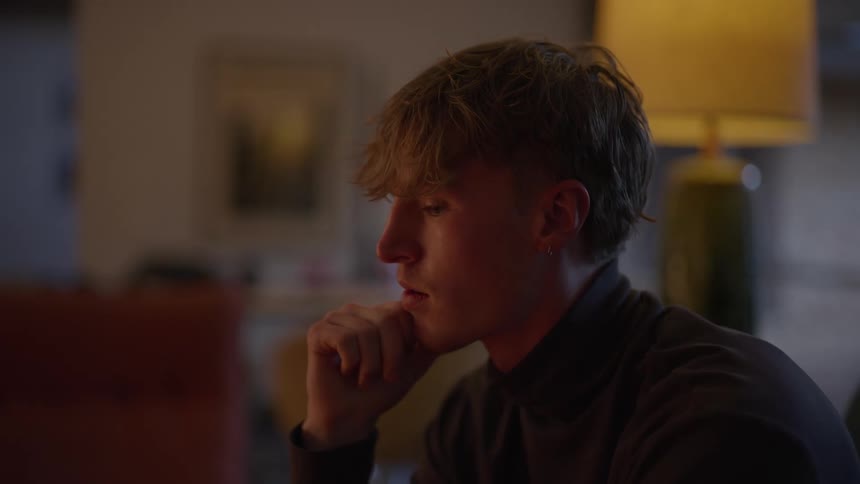 Man rests his face on his hand looking thoughtfully ahead
