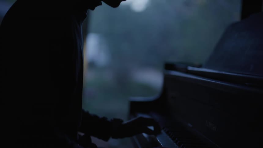 A man is playing the piano in the dark