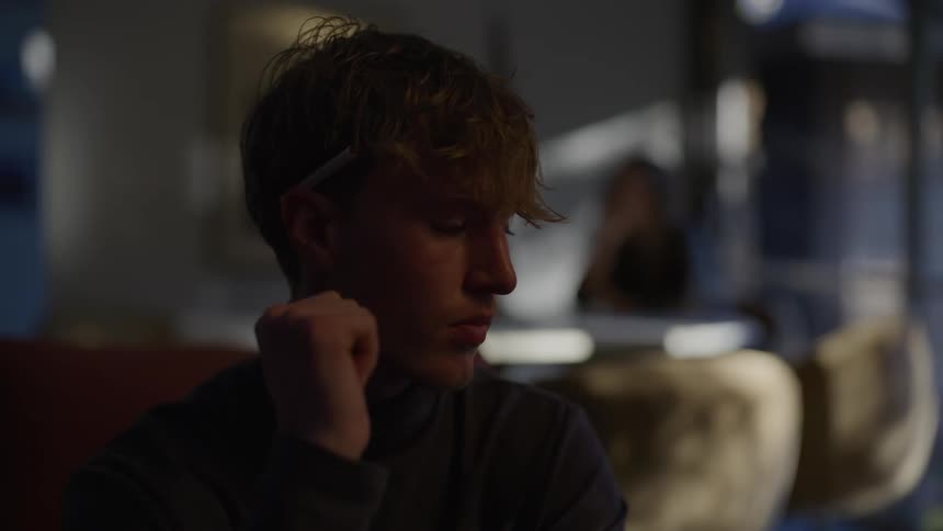 The face of a young man who is thoughtful and with his hand on his chin in an indoor place