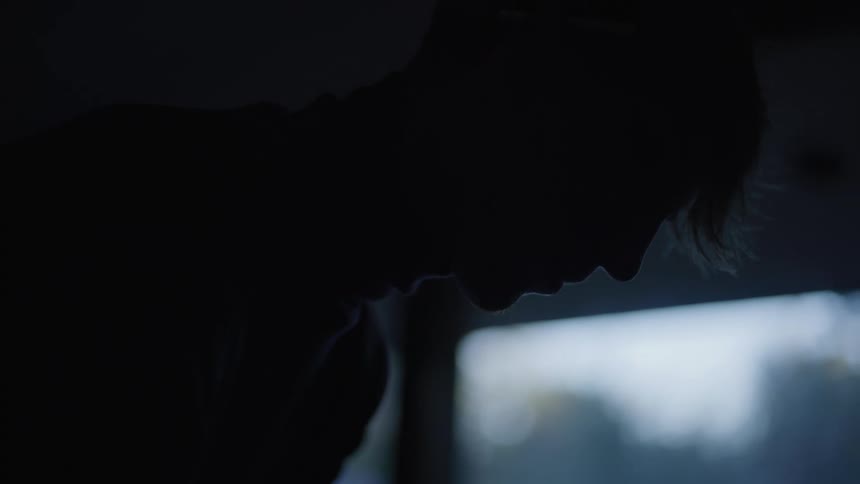Mans hands play the keys of a piano in a dark room