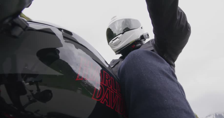 A person wearing a white helmet riding a black motorcycle