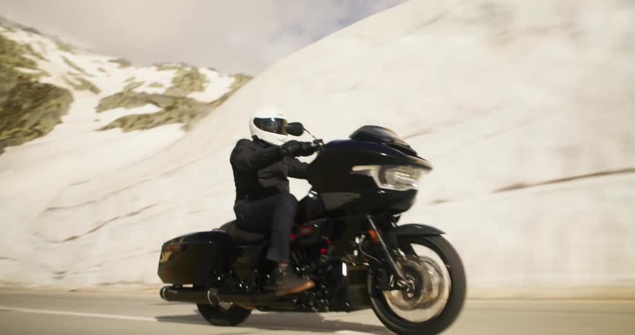 A man is riding a motorcycle on a highway in a snowy mountain area