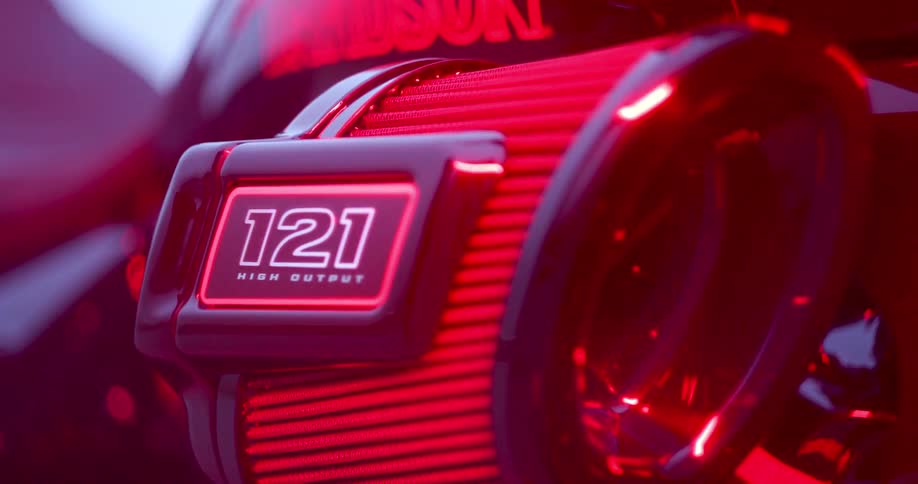 Closeup of a harleydavidson engine with red lighting highlighting the 121 high output emblem