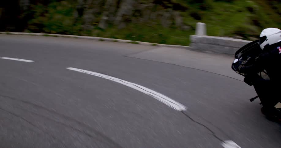 A person is driving on a long mountain road on a motorcycle