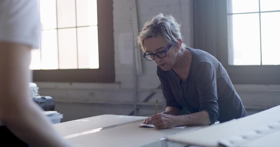 A woman is writing on a paper on top of a box