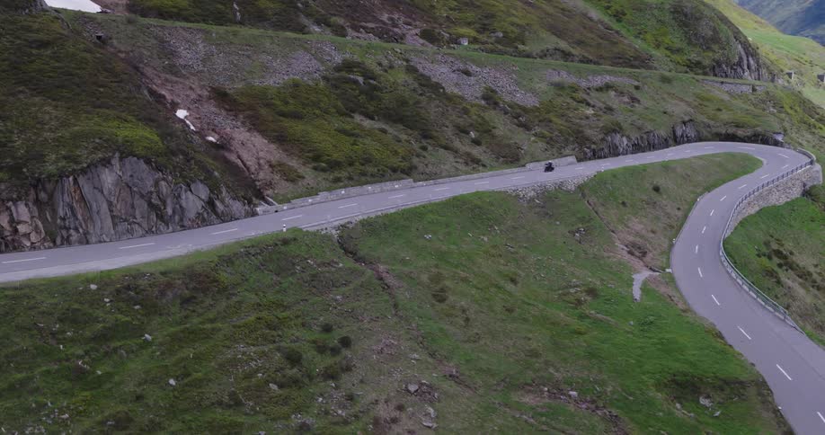 A motorcycle makes steep turns on the mountain road