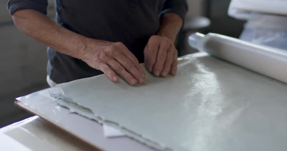 A man is inspecting a roll of wallpaper