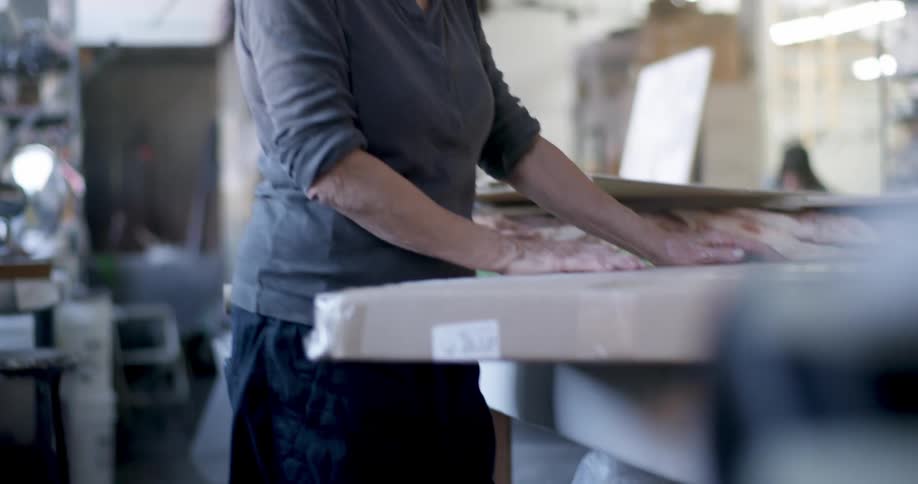Woman handles a large roll of material on a table in a studio