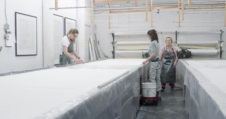 Women talk as they work on an assembly line