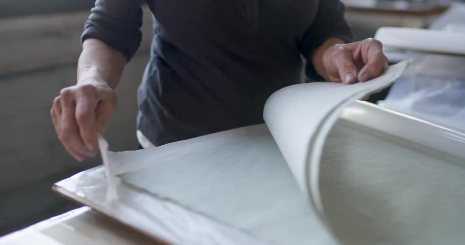 Woman looks through pieces of fabric sandwiched between plastic sheets
