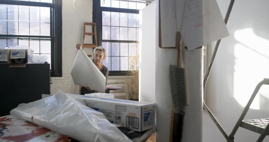 A woman unrolls paper from a roll