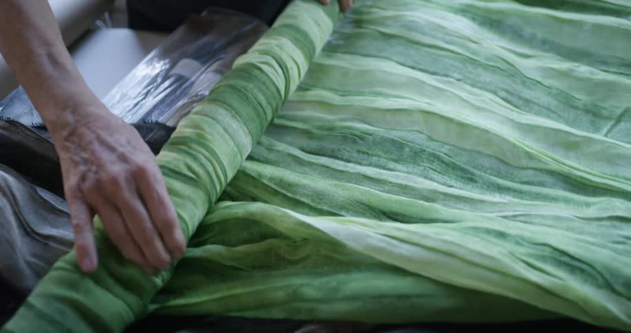 A person is rolling up fabric in the shop