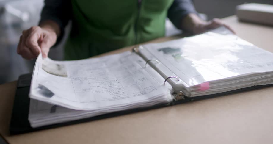 Person leafs through a thick binder with protective plastic sheets