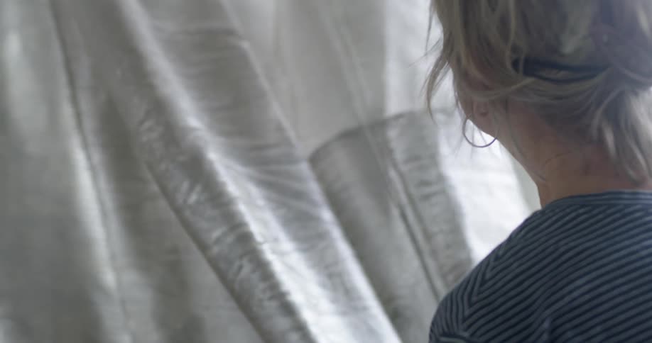 A middle aged blonde woman checks the fabric of a brown curtain