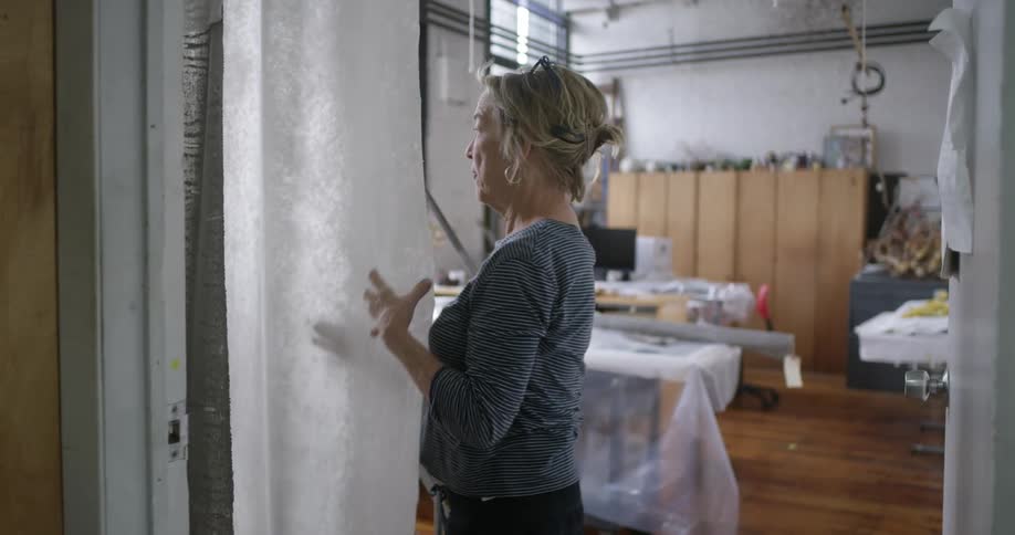 A woman folds a roll of fabric and moves it