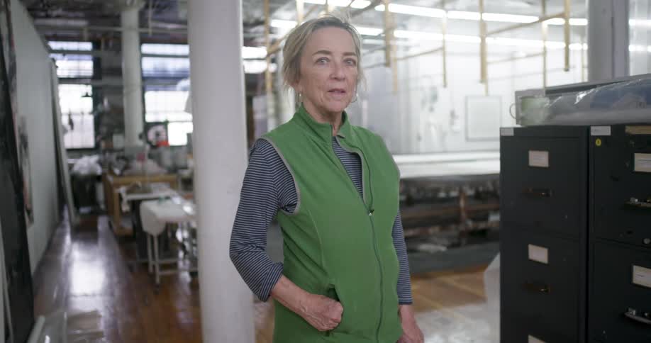 Woman in green vest is standing in a studio