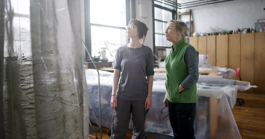 Two women discuss something high in front of them