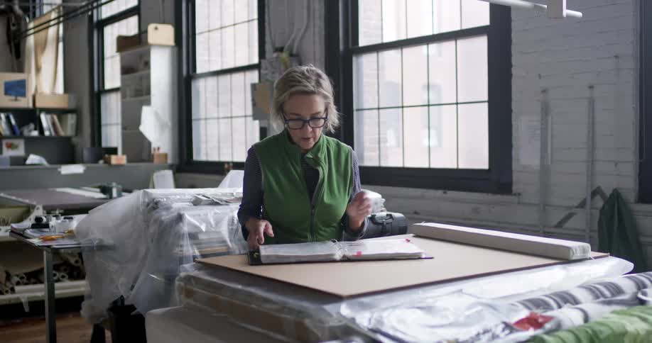A woman in a room with fabric looks through a book