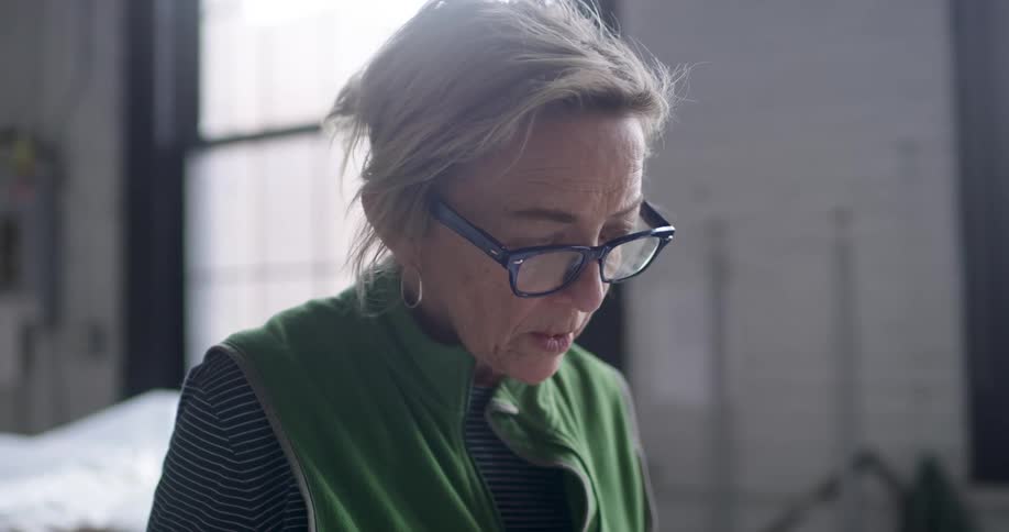 A woman moves her head back and forth as she looks at something below her