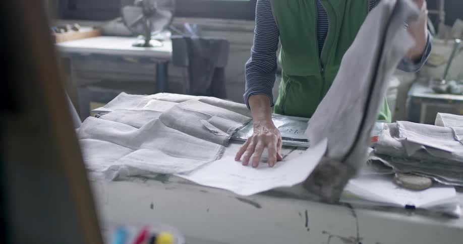 Woman at a table working with fabrics in a factory