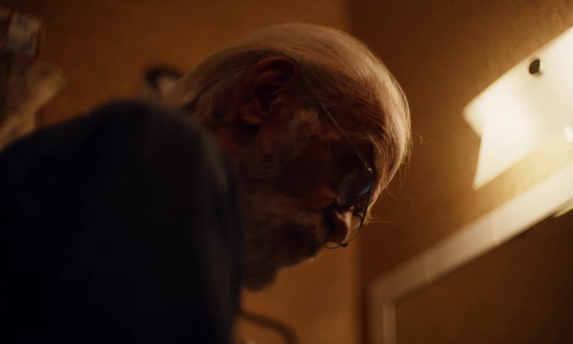 Elderly man standing in front of bathroom mirror combing his hair