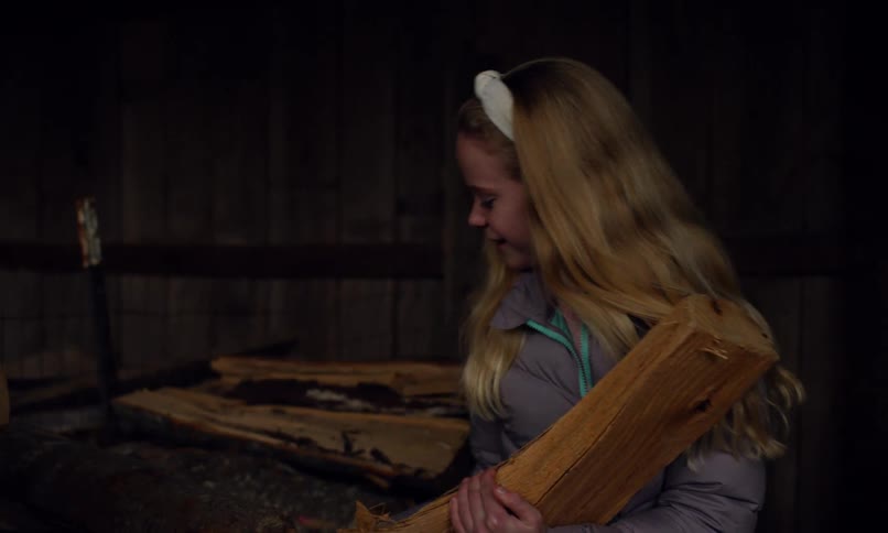 Girl in a shed collecting pieces of firewood
