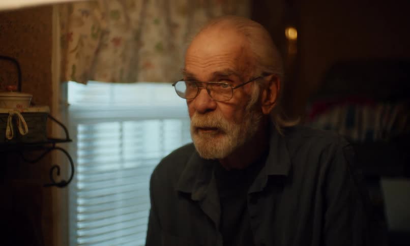 Elderly man combing his hair in front of the bathroom mirror